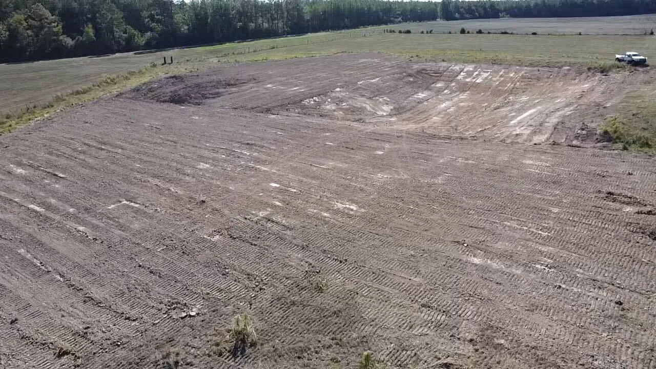 Aerial view of a freshly graded field between the tree lines